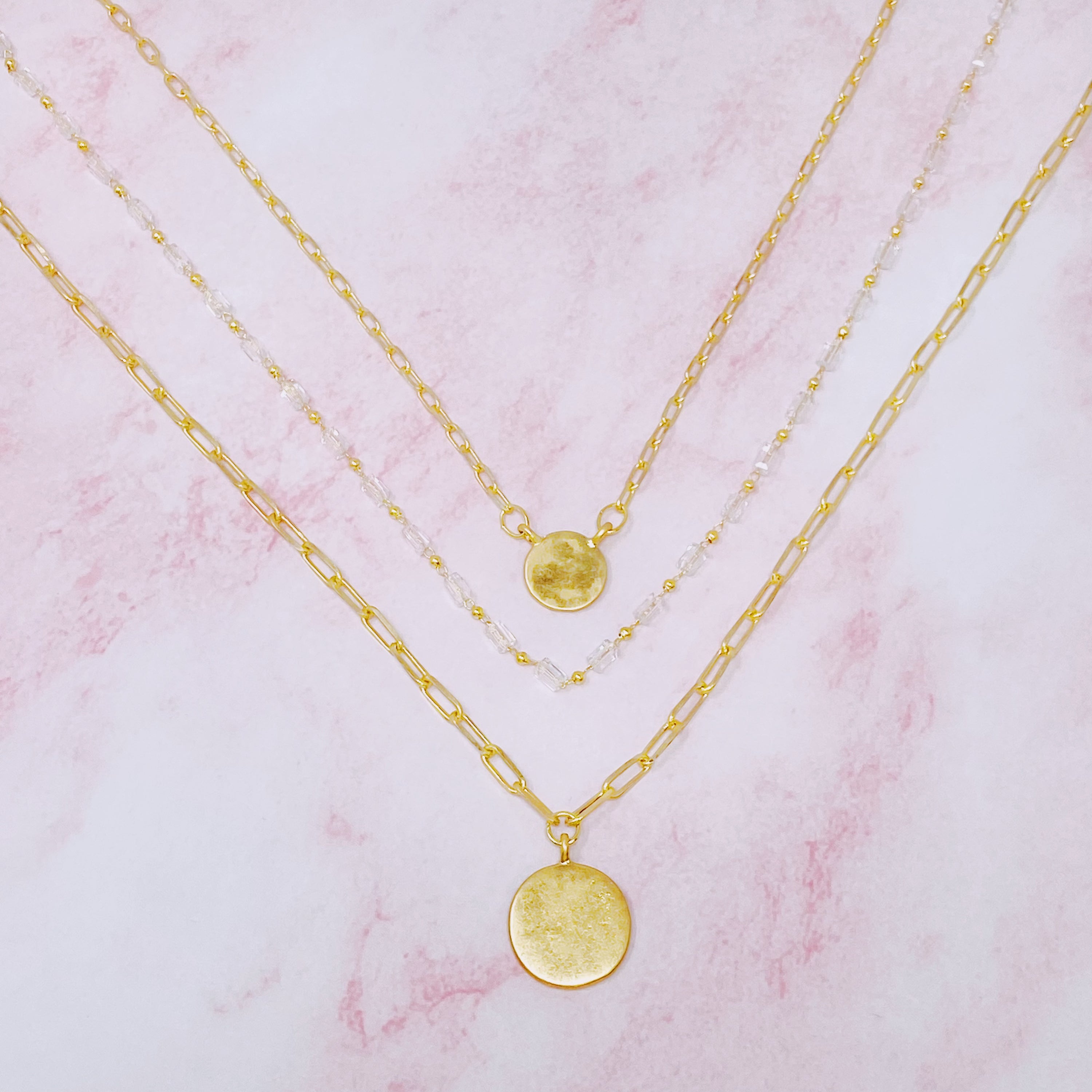 A stylish set of three necklaces featuring disc pendants and beaded designs, perfect for layering and versatile fashion.