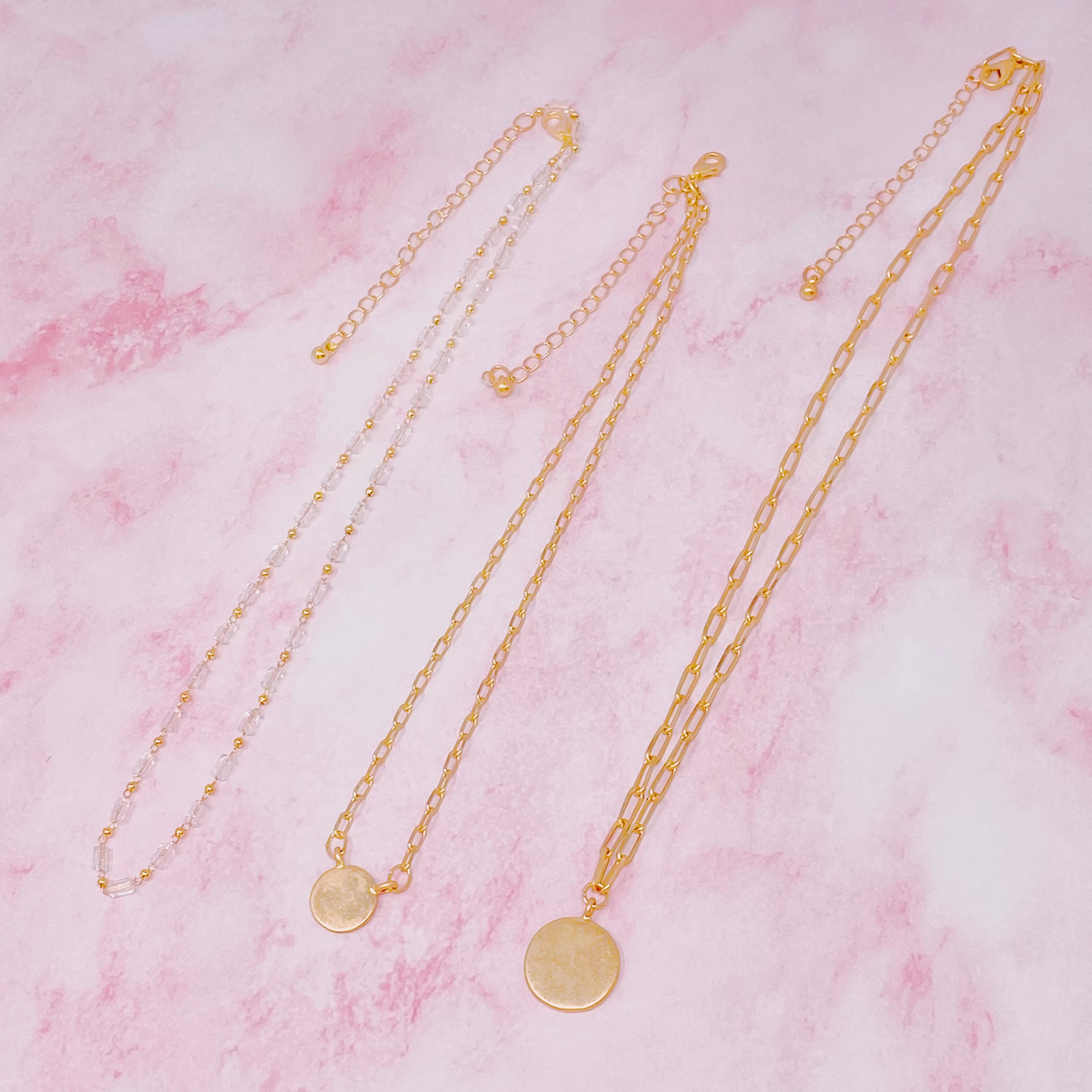 A stylish set of three necklaces featuring disc pendants and beaded designs, perfect for layering and versatile fashion.