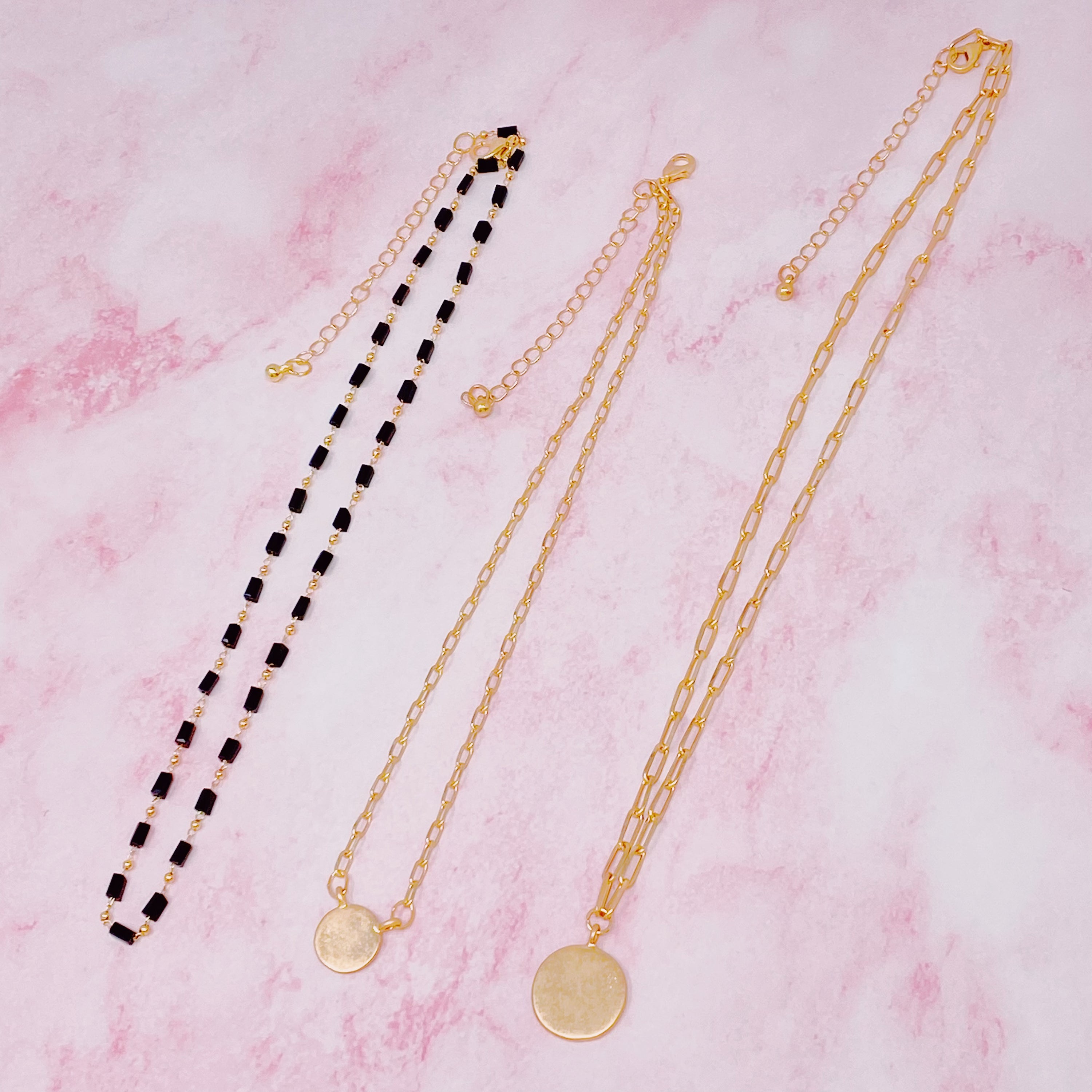 A stylish set of three necklaces featuring disc pendants and beaded designs, perfect for layering and versatile fashion.