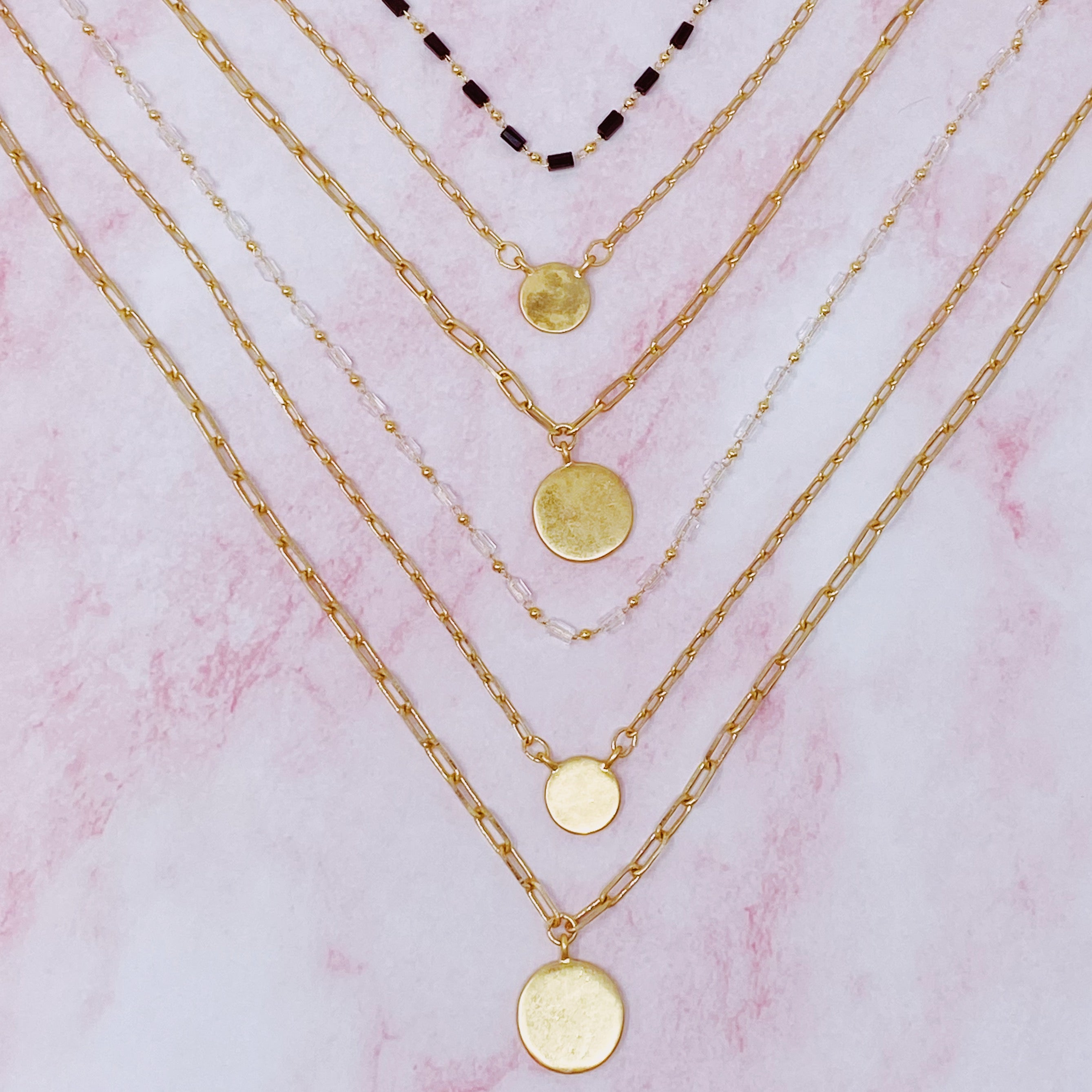A stylish set of three necklaces featuring disc pendants and beaded designs, perfect for layering and versatile fashion.