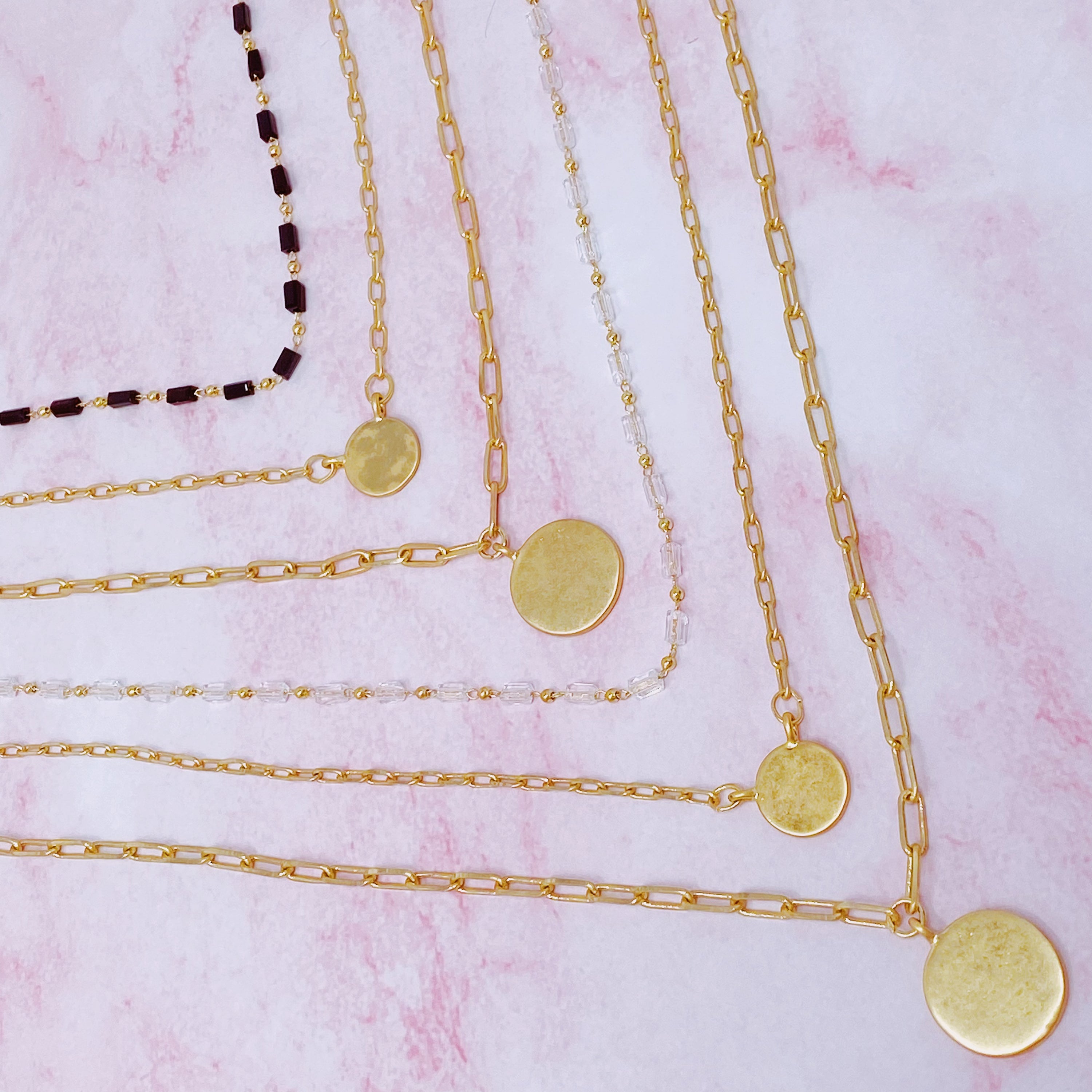 A stylish set of three necklaces featuring disc pendants and beaded designs, perfect for layering and versatile fashion.