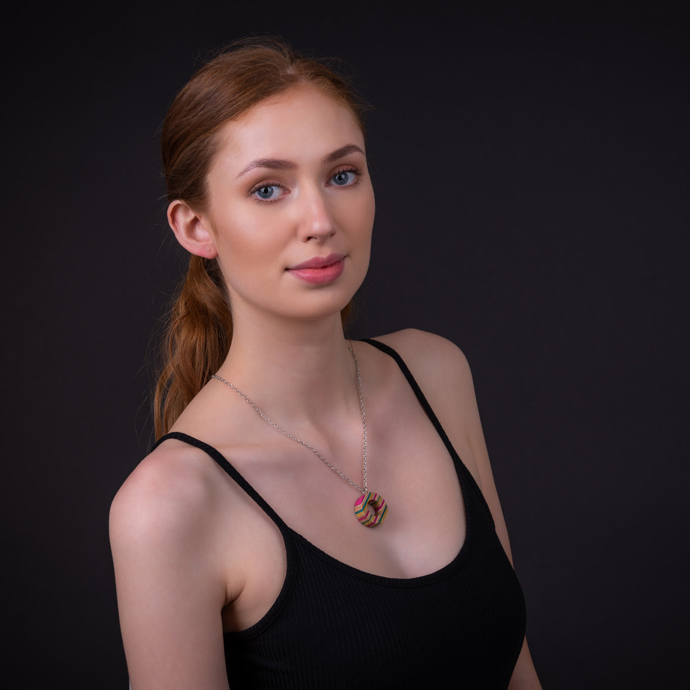 A unique Donut Eco Friendly Recycled Skateboard Necklace featuring vibrant colors and patterns, handcrafted from upcycled skateboards with a stainless steel chain.