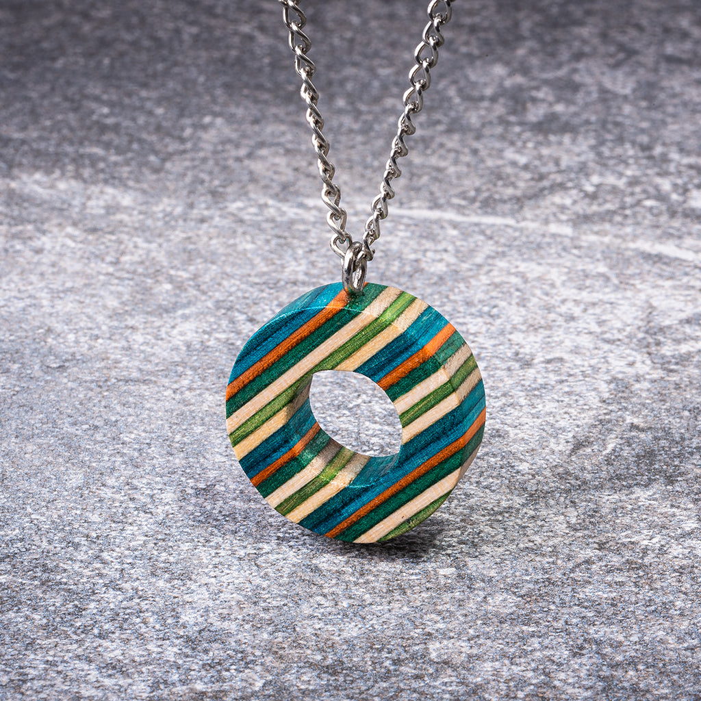 A unique Donut Eco Friendly Recycled Skateboard Necklace featuring vibrant colors and patterns, handcrafted from upcycled skateboards with a stainless steel chain.