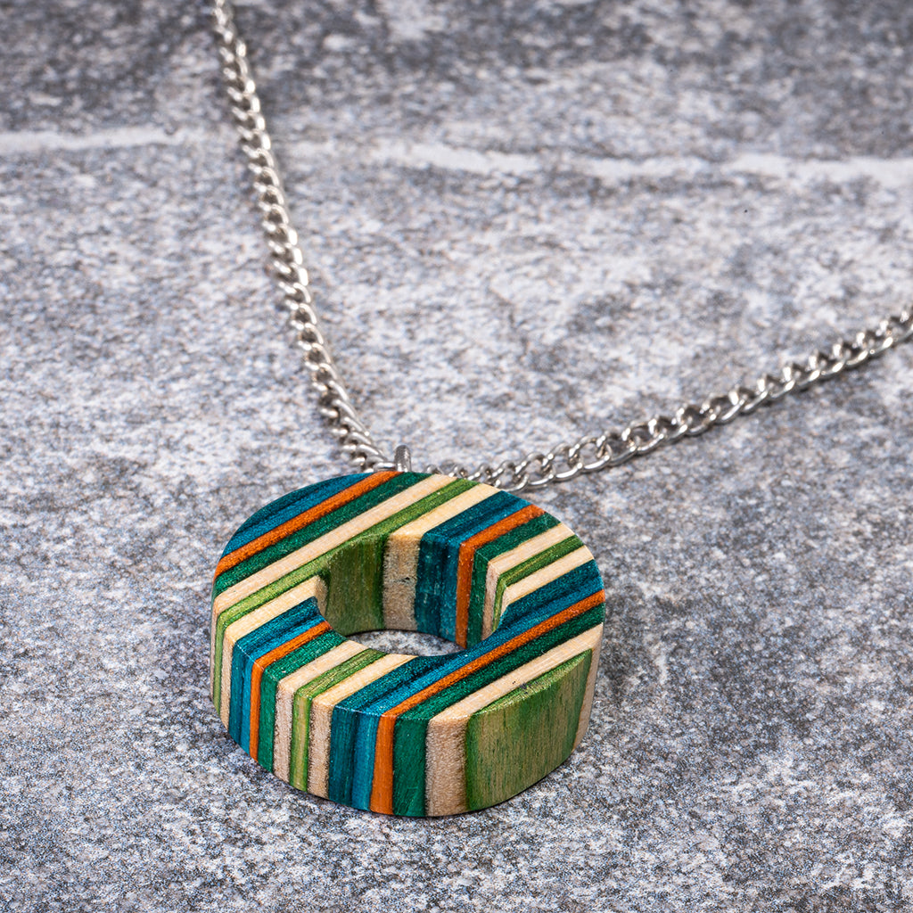 A unique Donut Eco Friendly Recycled Skateboard Necklace featuring vibrant colors and patterns, handcrafted from upcycled skateboards with a stainless steel chain.