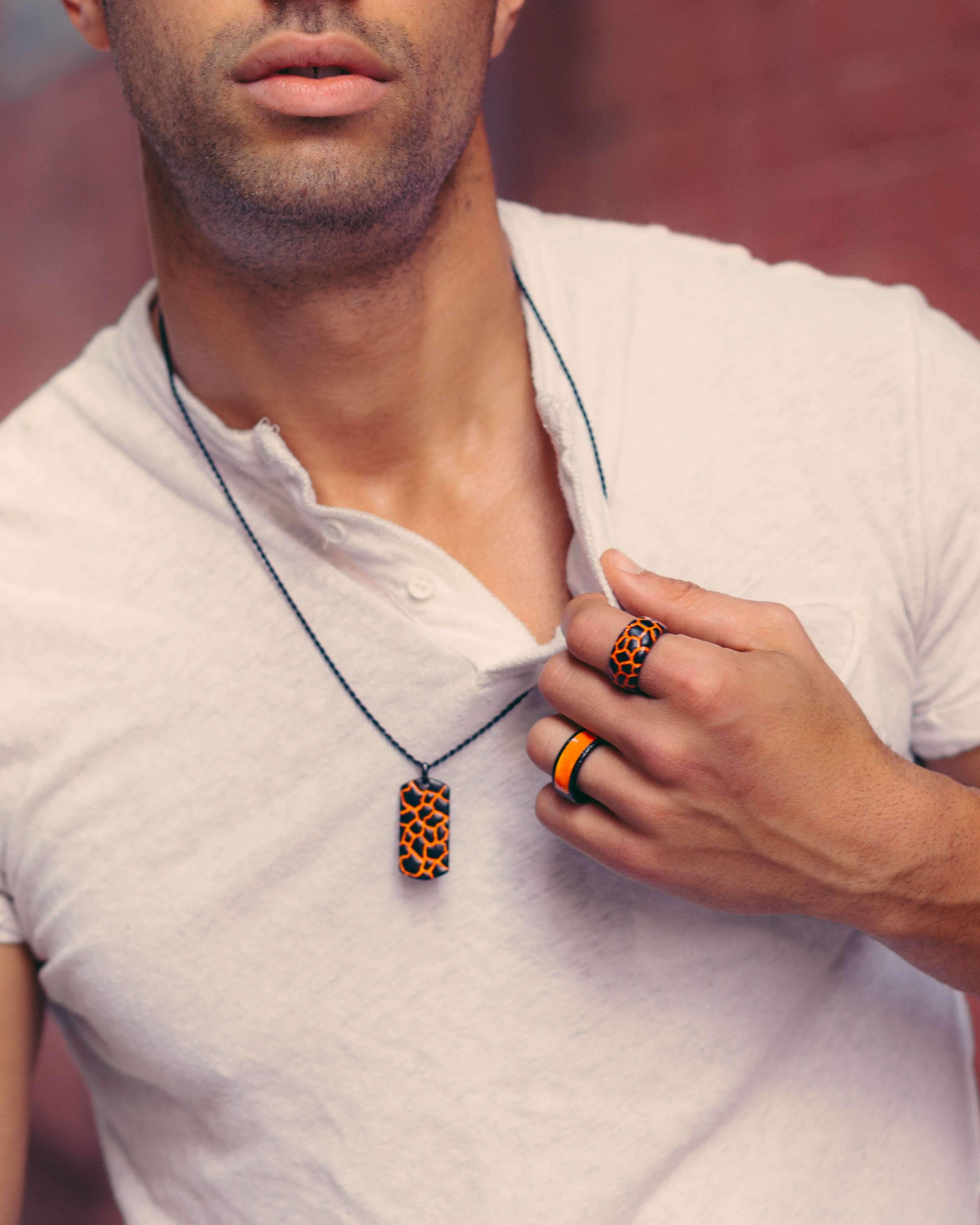 Earth & Fire Black Rhodium Plated Sterling Silver Tag with red and orange enamel, showcasing textured design inspired by lava.