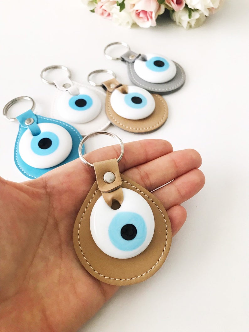 Elegant evil eye leather keychain featuring turquoise and white evil eye beads, perfect for keys or bags.