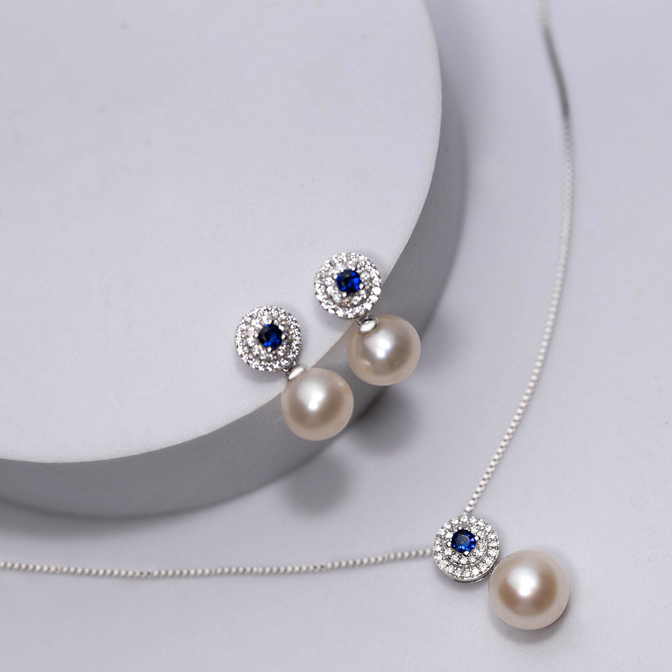 Elegant Freshwater Pearl Earrings with sapphire blue cubic zirconia, showcasing round white pearls and sterling silver with gold plating.