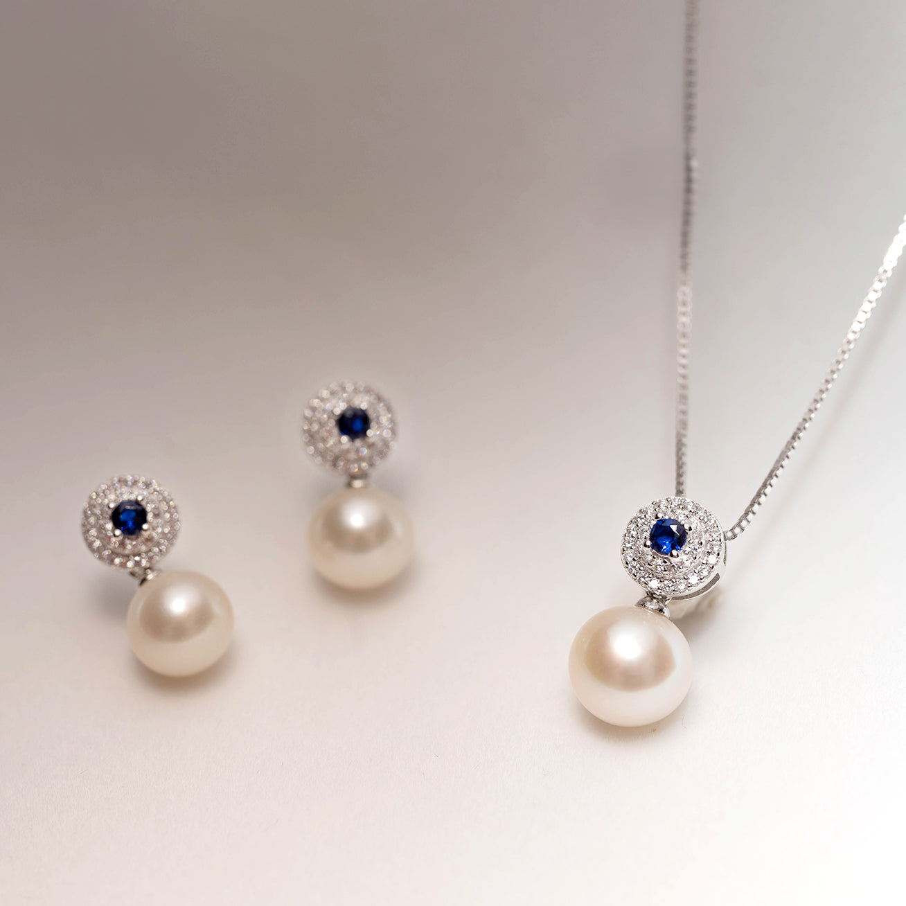 Elegant Freshwater Pearl Earrings with sapphire blue cubic zirconia, showcasing round white pearls and sterling silver with gold plating.