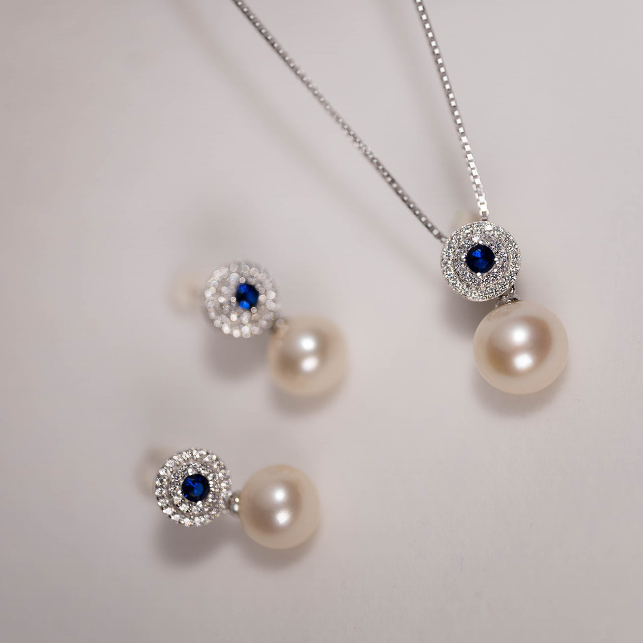 Elegant Freshwater Pearl Earrings with sapphire blue cubic zirconia, showcasing round white pearls and sterling silver with gold plating.