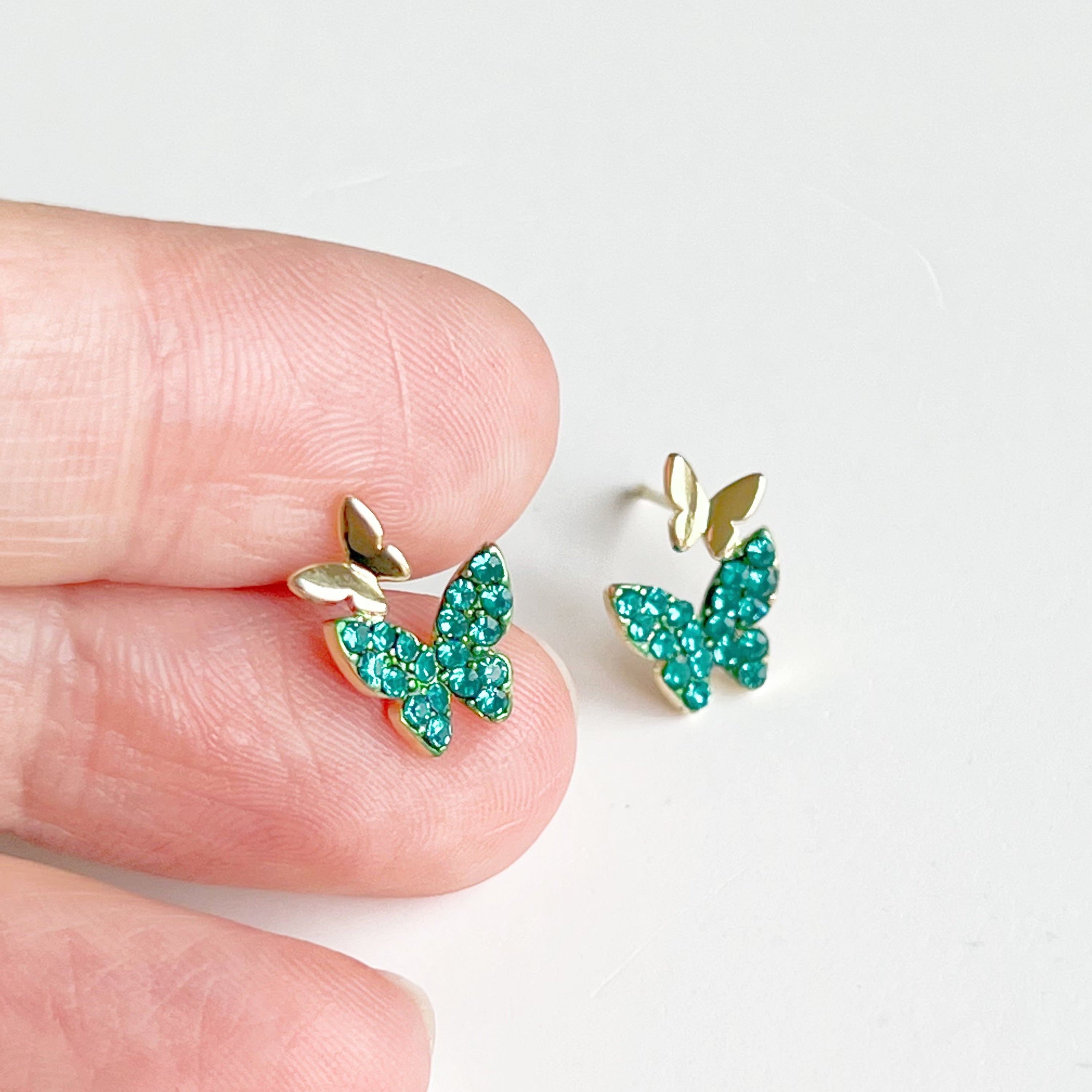 Emerald green crystal butterflies earrings made of gold-plated sterling silver and bronze, featuring sparkling green zircon stones.