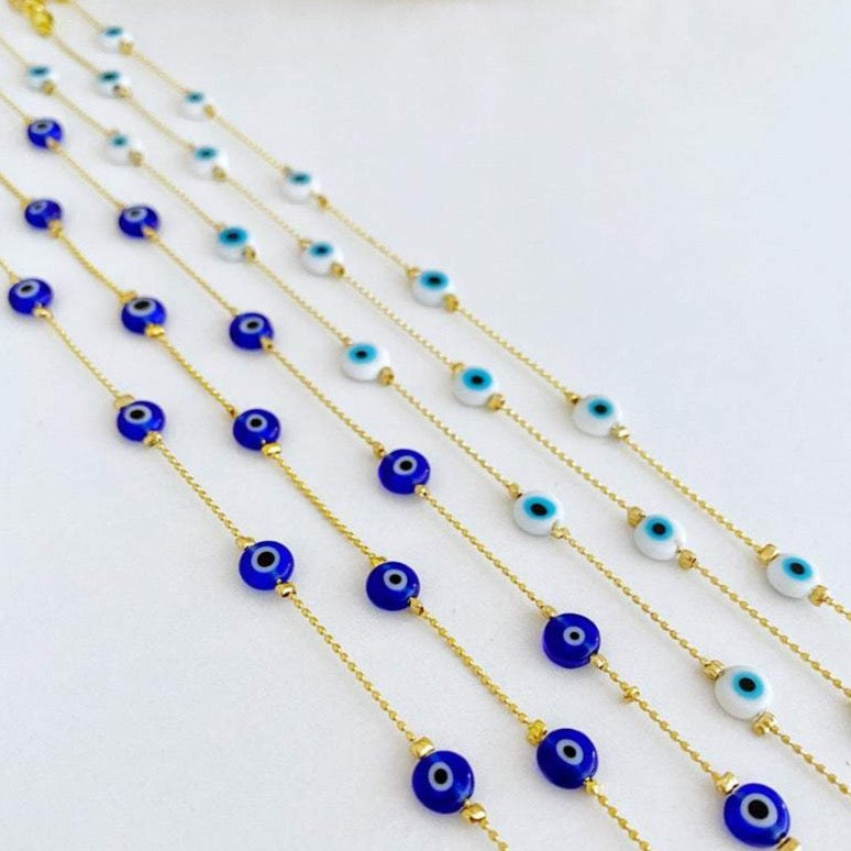 A delicate gold chain anklet featuring tiny blue and white evil eye beads, perfect for minimalist jewelry lovers.