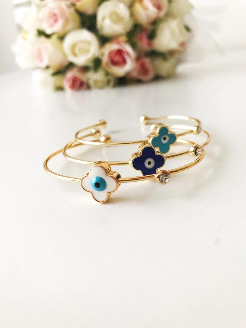 Evil Eye Bangle Bracelet featuring a movable oval charm and clover design in various colors, made from durable stainless steel.