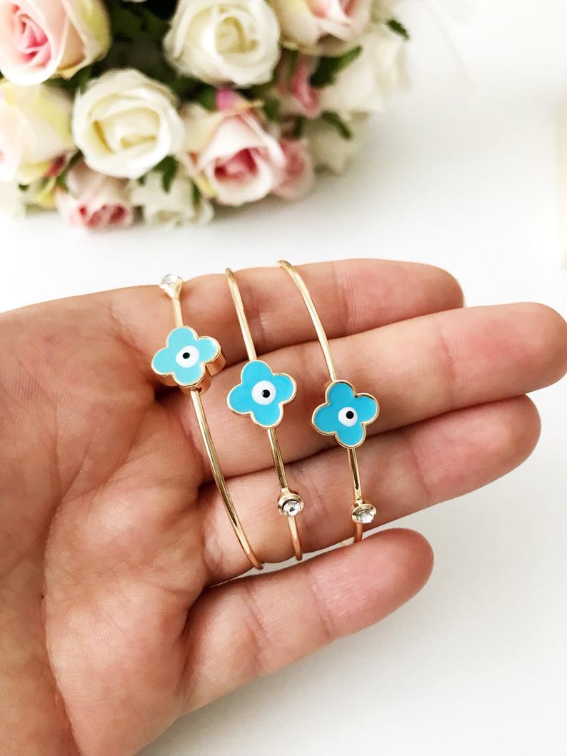 Evil Eye Bangle Bracelet featuring a movable oval charm and clover design in various colors, made from durable stainless steel.