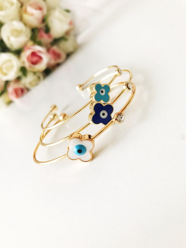 Evil Eye Bangle Bracelet featuring a movable oval charm and clover design in various colors, made from durable stainless steel.