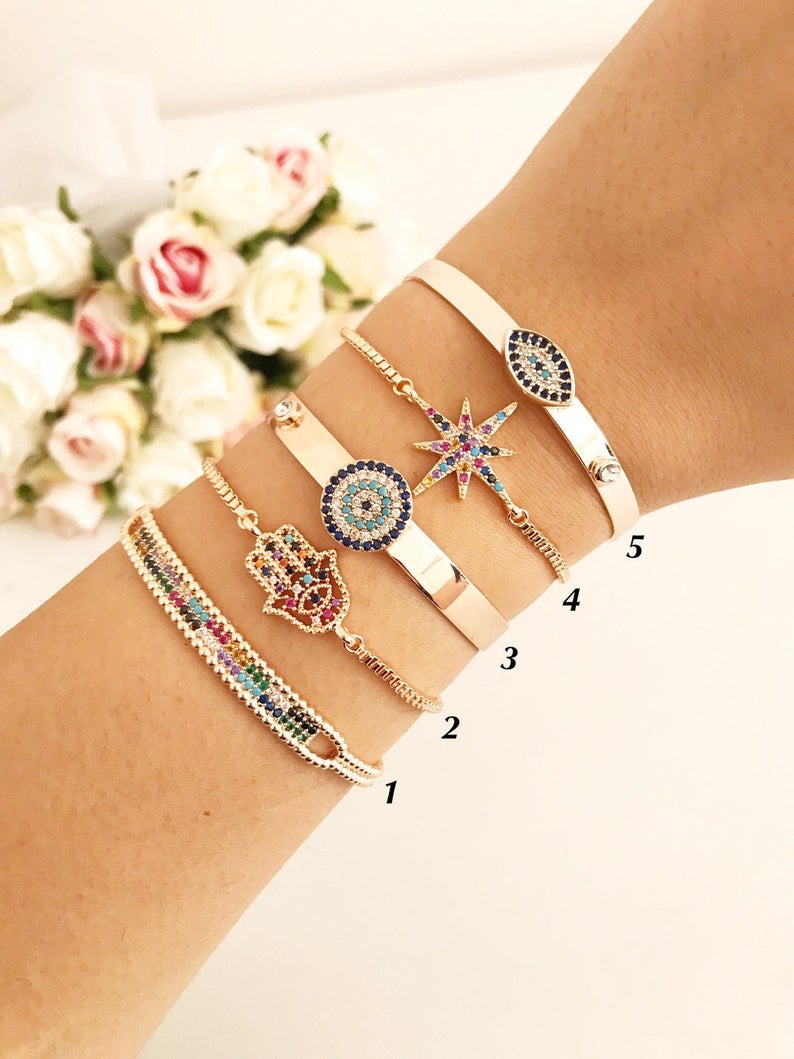 A beautiful rose gold Evil Eye Bangle Bracelet featuring rainbow zirconia beads, showcasing its adjustable design and elegant charm.