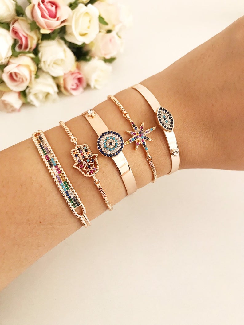 A beautiful rose gold Evil Eye Bangle Bracelet featuring rainbow zirconia beads, showcasing its adjustable design and elegant charm.
