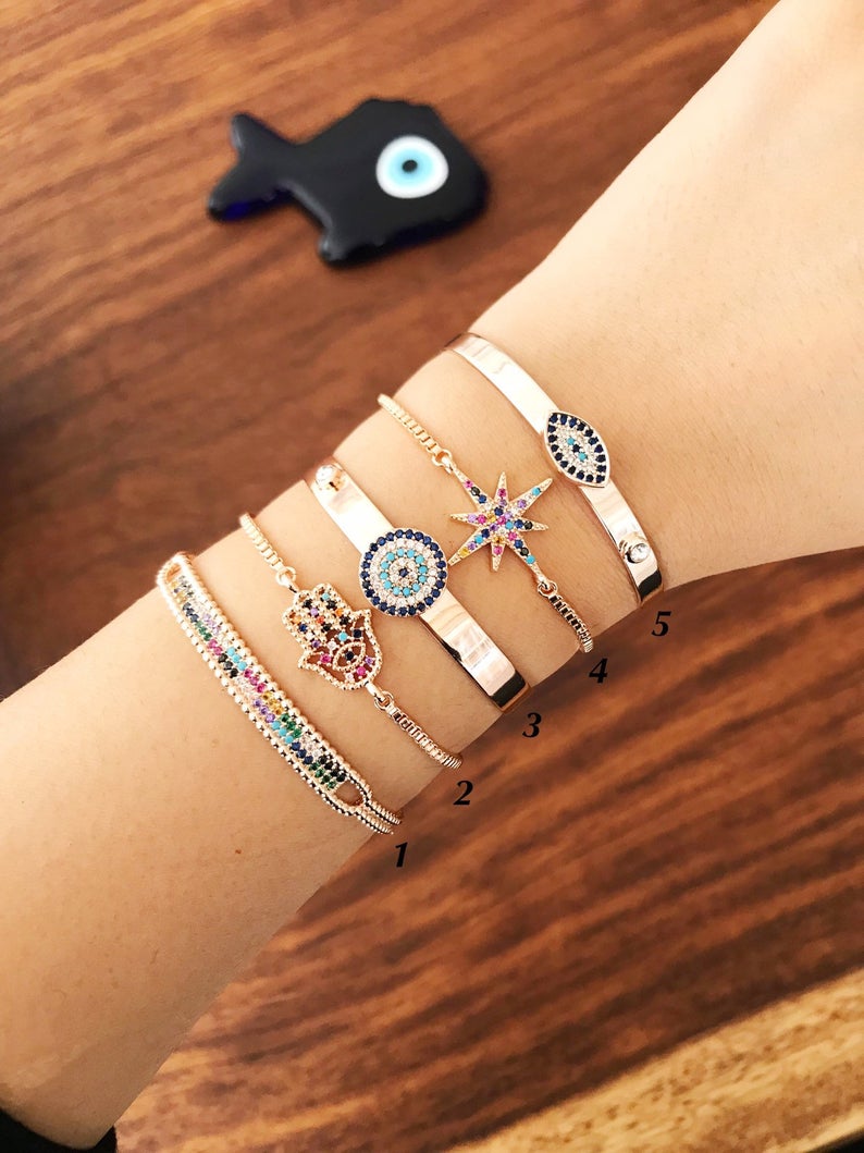 A beautiful rose gold Evil Eye Bangle Bracelet featuring rainbow zirconia beads, showcasing its adjustable design and elegant charm.