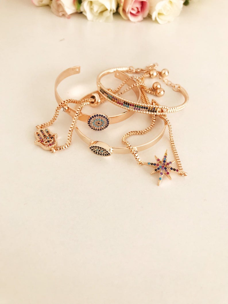 A beautiful rose gold Evil Eye Bangle Bracelet featuring rainbow zirconia beads, showcasing its adjustable design and elegant charm.