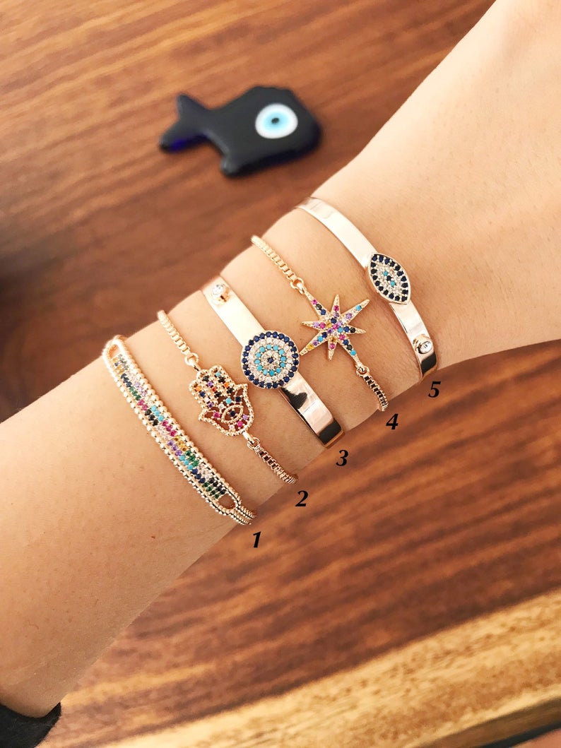 A beautiful rose gold Evil Eye Bangle Bracelet featuring rainbow zirconia beads, showcasing its adjustable design and elegant charm.