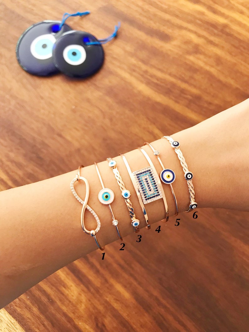 Rose gold Evil Eye Bangle Bracelet featuring a movable oval charm and adjustable cuff design, perfect for everyday wear.
