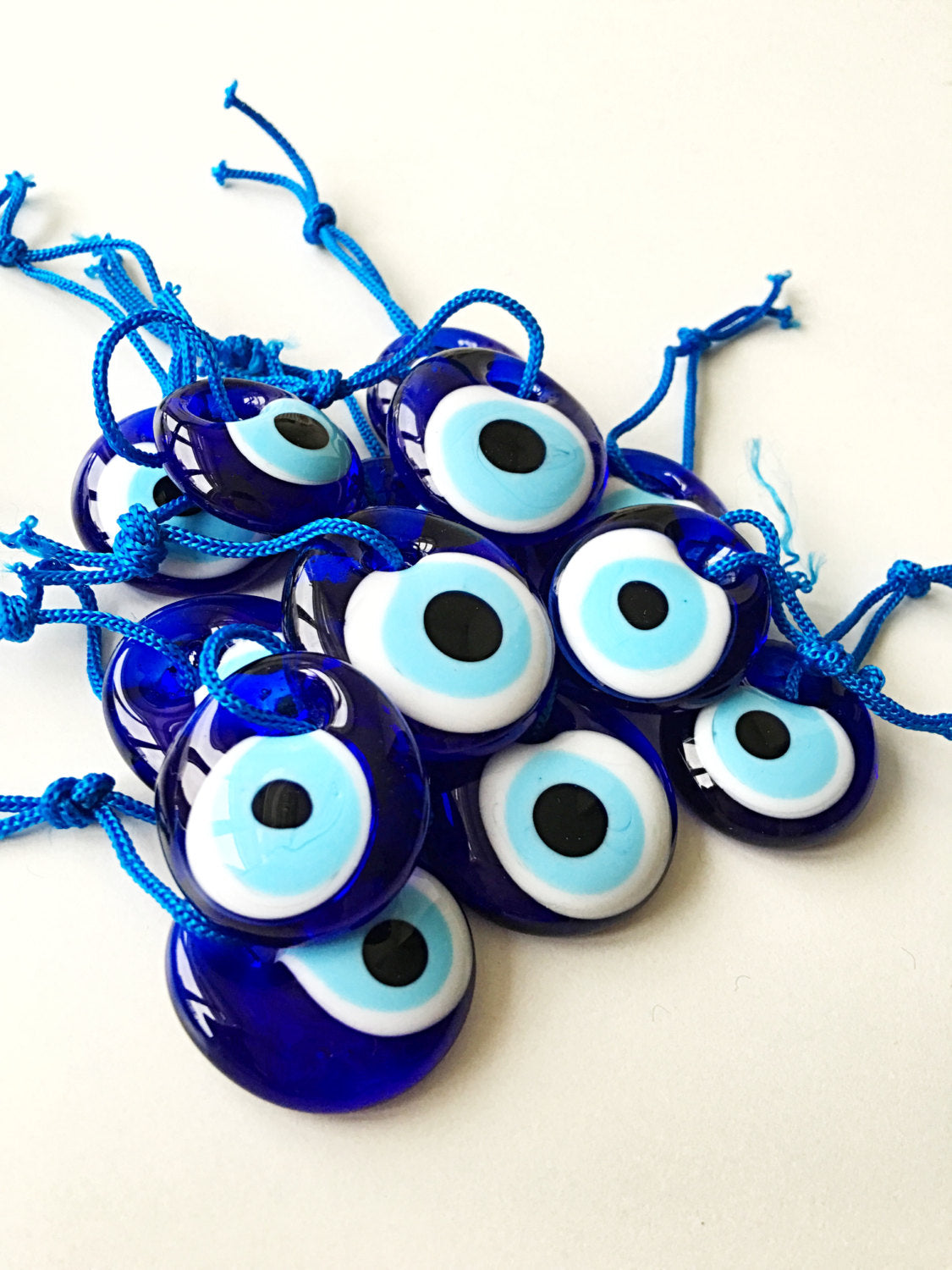 A set of five 3.5cm handmade evil eye beads with blue rope, featuring intricate designs for wall hanging or car charm.