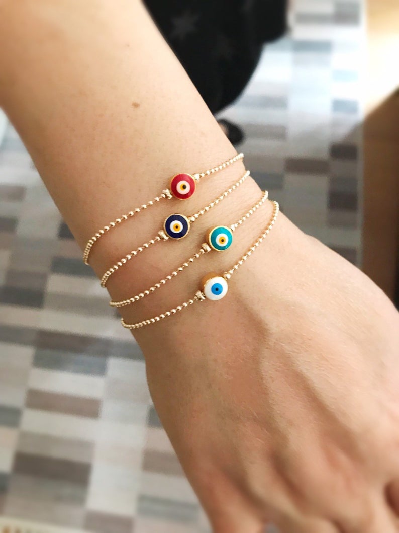 A stylish Evil Eye Bead Bracelet featuring a blue evil eye bead on a delicate gold chain, showcasing its minimalist design and adjustable length.