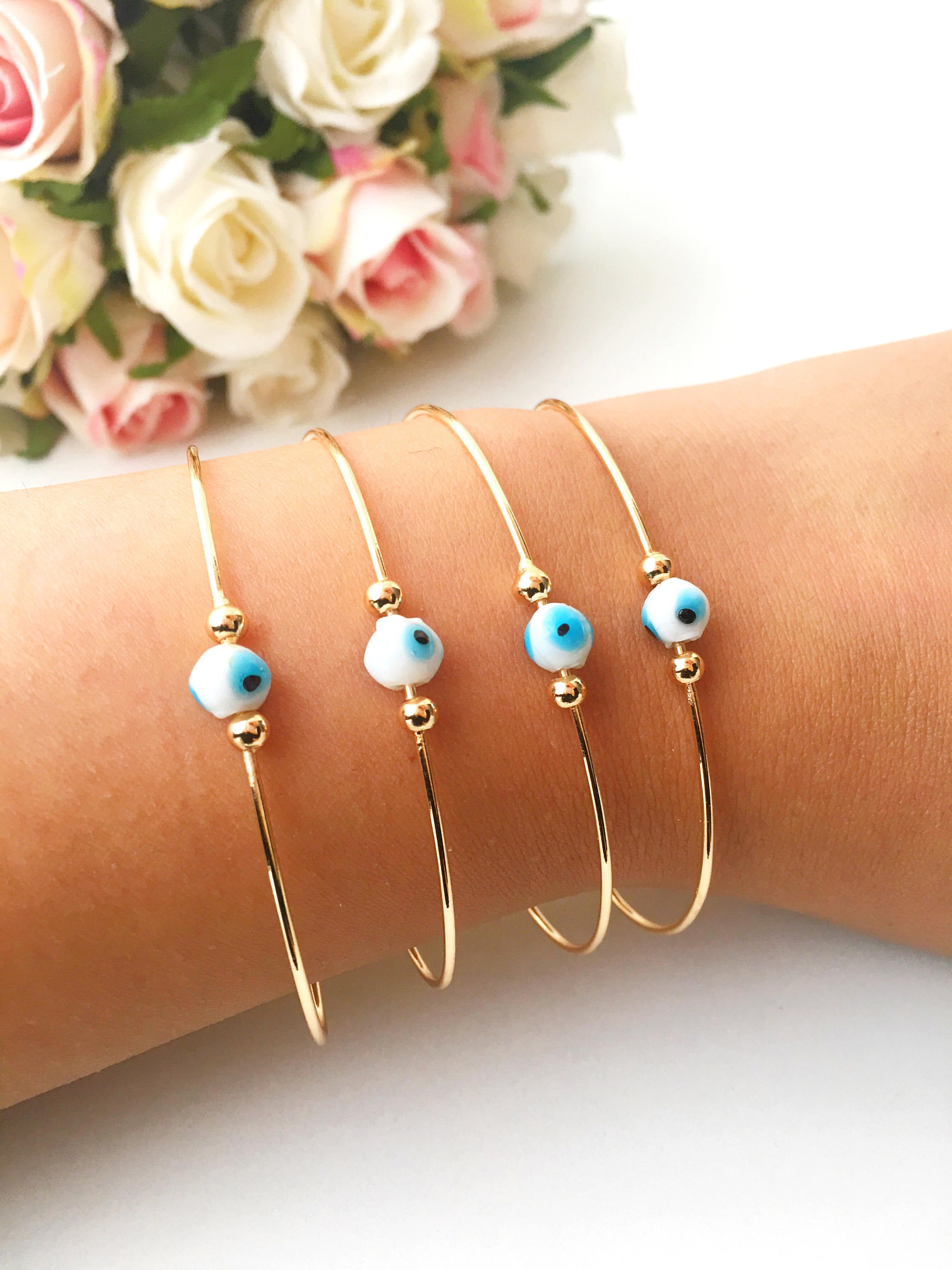 Evil Eye Beaded Bangle Bracelet in Gold Rose featuring a movable blue evil eye charm and adjustable stainless steel design.