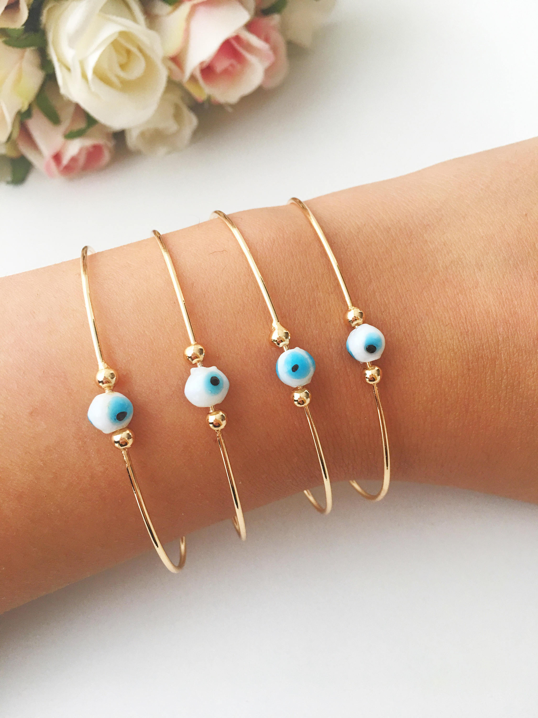 Evil Eye Beaded Bangle Bracelet in Gold Rose featuring a movable blue evil eye charm and adjustable stainless steel design.