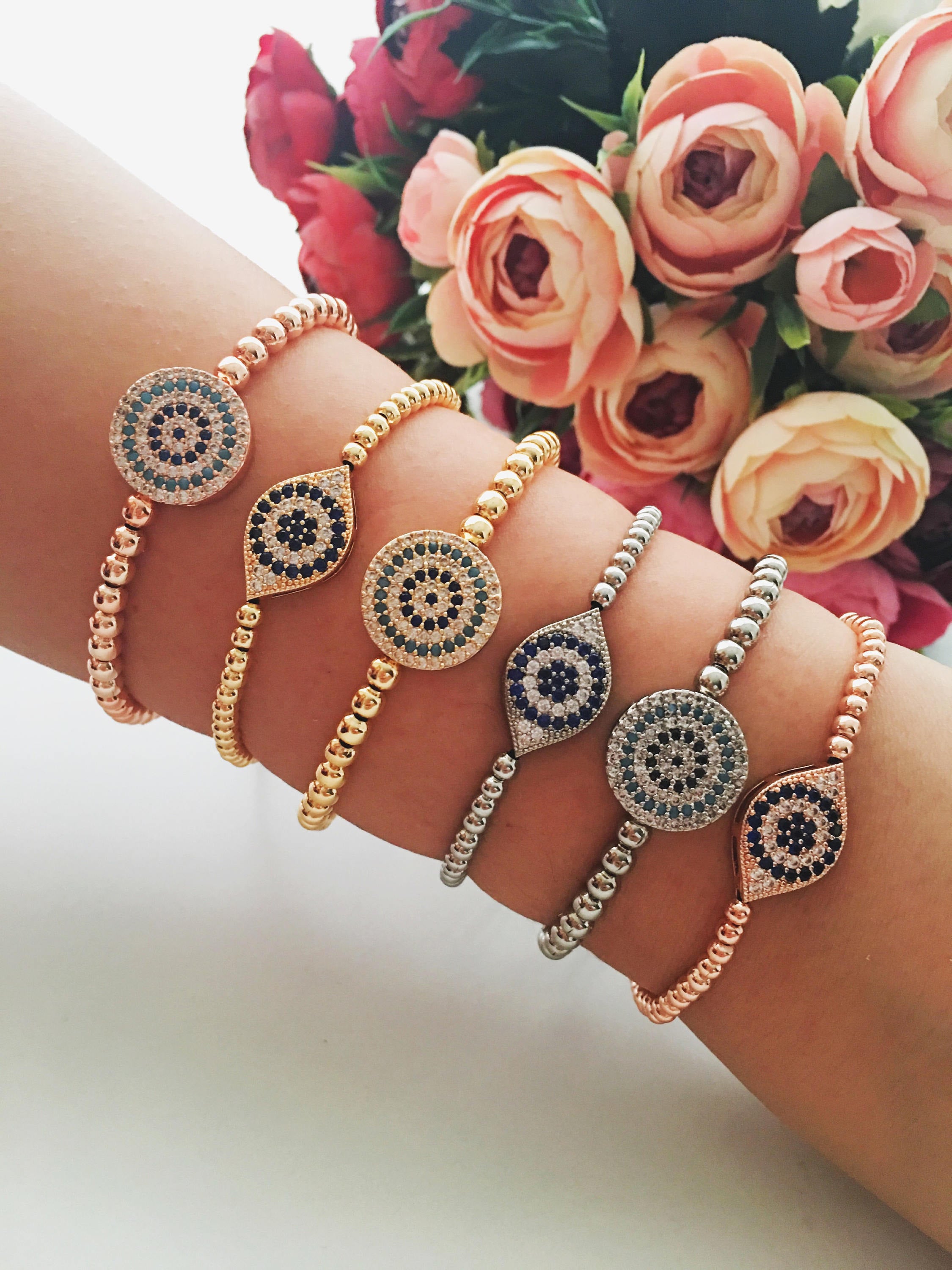 A stunning Evil Eye Beaded Bracelet featuring a zirconia evil eye charm, adjustable design, and available in rose gold and silver finishes.