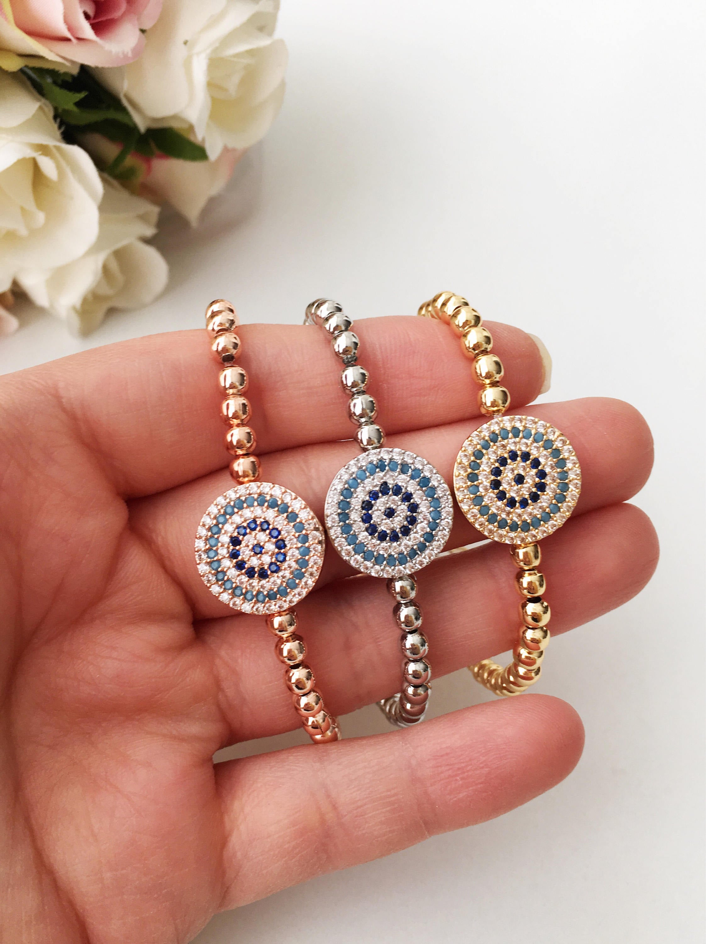 A stunning Evil Eye Beaded Bracelet featuring a zirconia evil eye charm, adjustable design, and available in rose gold and silver finishes.