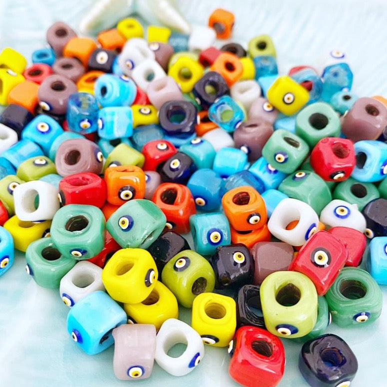 Handmade Murano glass Evil Eye beads in 12mm cube shape, showcasing vibrant colors and intricate designs, perfect for jewelry making.