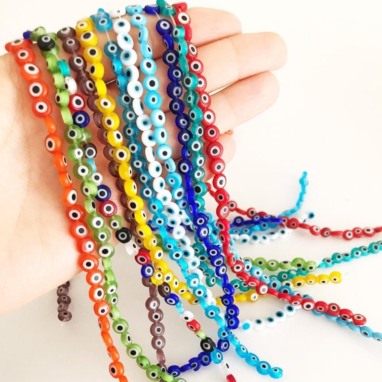 A strand of 6mm Evil Eye beads in various colors, showcasing their flat round shape and handmade quality.