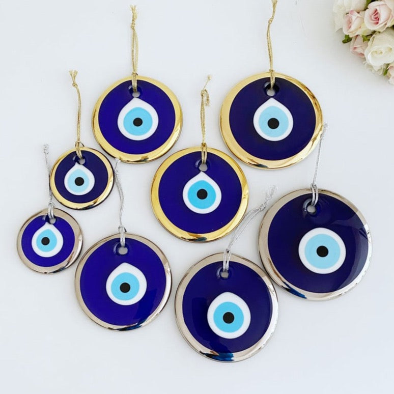A collection of Evil Eye Beads in gold and silver, showcasing various sizes from 7cm to 13cm, made of handmade blue glass.