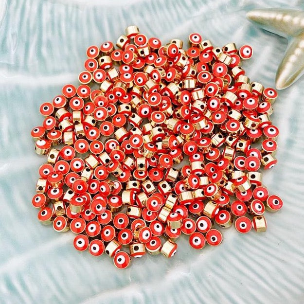 A collection of vibrant orange evil eye beads made of brass, featuring gold connectors, ideal for DIY jewelry making.