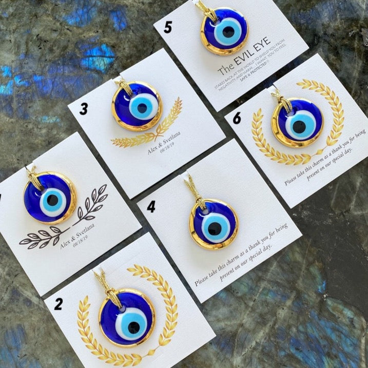A collection of beautiful glass Evil Eye Beads in vibrant colors, perfect for personalized wedding favors, displayed with custom cards.