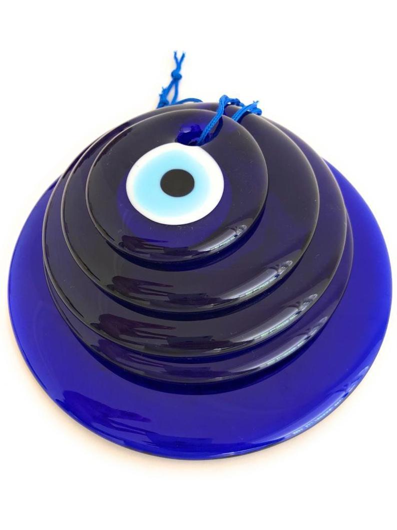 A collection of blue glass evil eye beads in various sizes, showcasing their round shape and vibrant color, perfect for wall hangings and tree decor.