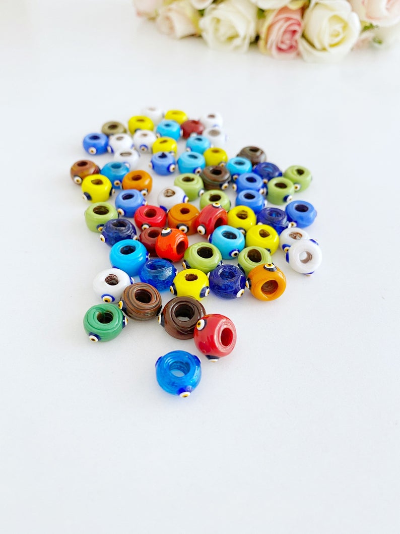 A collection of colorful handmade Murano glass Evil Eye beads, showcasing intricate designs and vibrant colors, perfect for jewelry making.