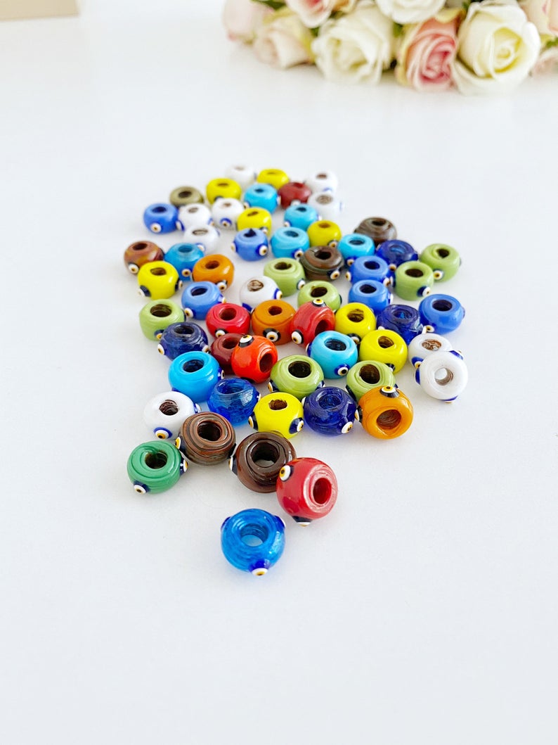 A collection of colorful handmade Murano glass Evil Eye beads, showcasing intricate designs and vibrant colors, perfect for jewelry making.