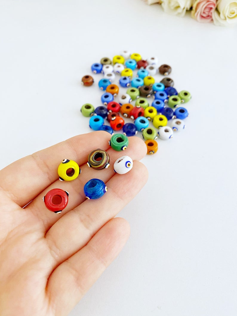A collection of colorful handmade Murano glass Evil Eye beads, showcasing intricate designs and vibrant colors, perfect for jewelry making.