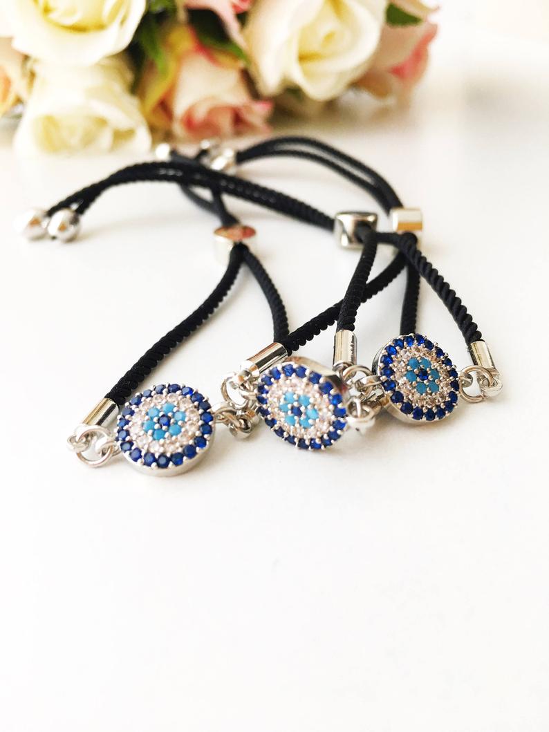 Adjustable Evil Eye Bracelet featuring a black string and a protective charm, available in silver, gold, and rose gold.