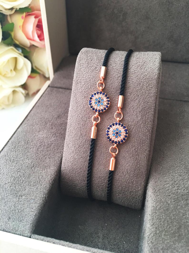 Adjustable Evil Eye Bracelet featuring a black string and a protective charm, available in silver, gold, and rose gold.