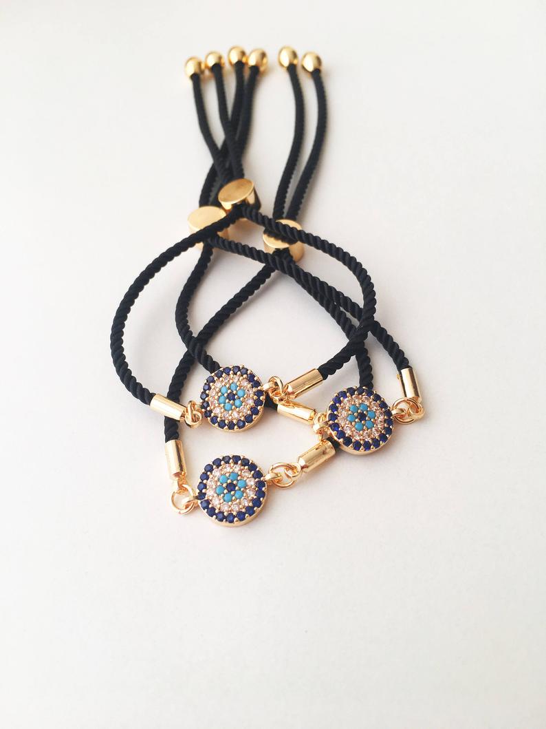Adjustable Evil Eye Bracelet featuring a black string and a protective charm, available in silver, gold, and rose gold.