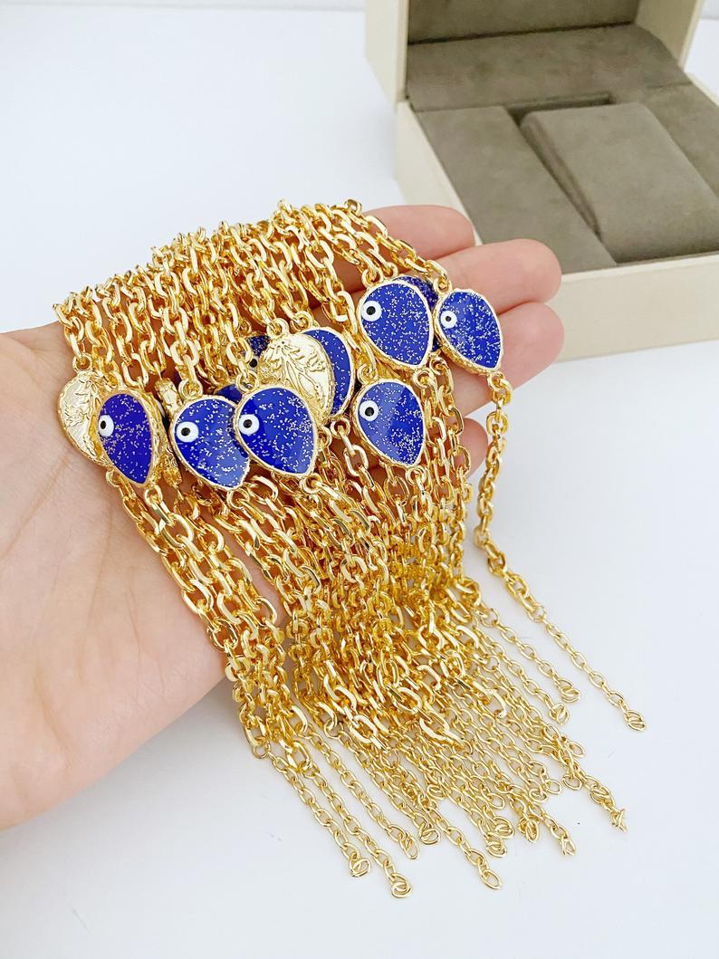 A beautiful Evil Eye Bracelet featuring a gold chain and a glittering teardrop evil eye charm, available in multiple colors.