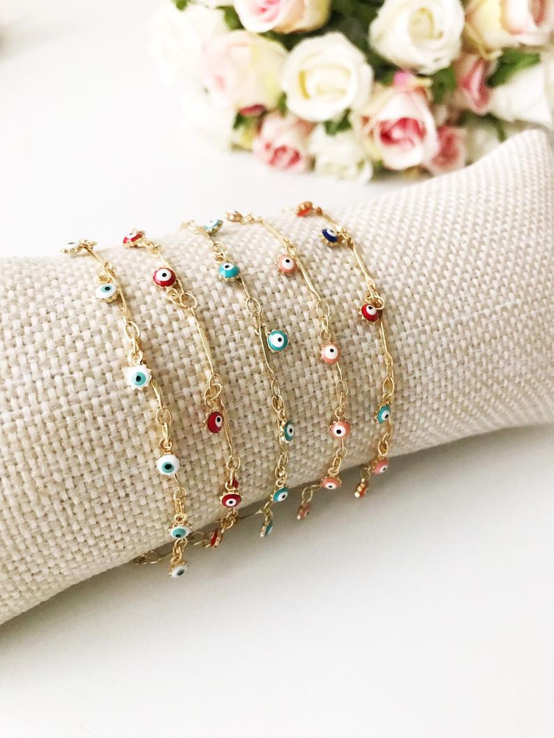 A delicate Evil Eye Bracelet featuring a gold chain and tiny blue evil eye bead, showcasing its minimalistic design.