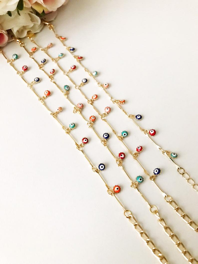 A delicate Evil Eye Bracelet featuring a gold chain and tiny blue evil eye bead, showcasing its minimalistic design.