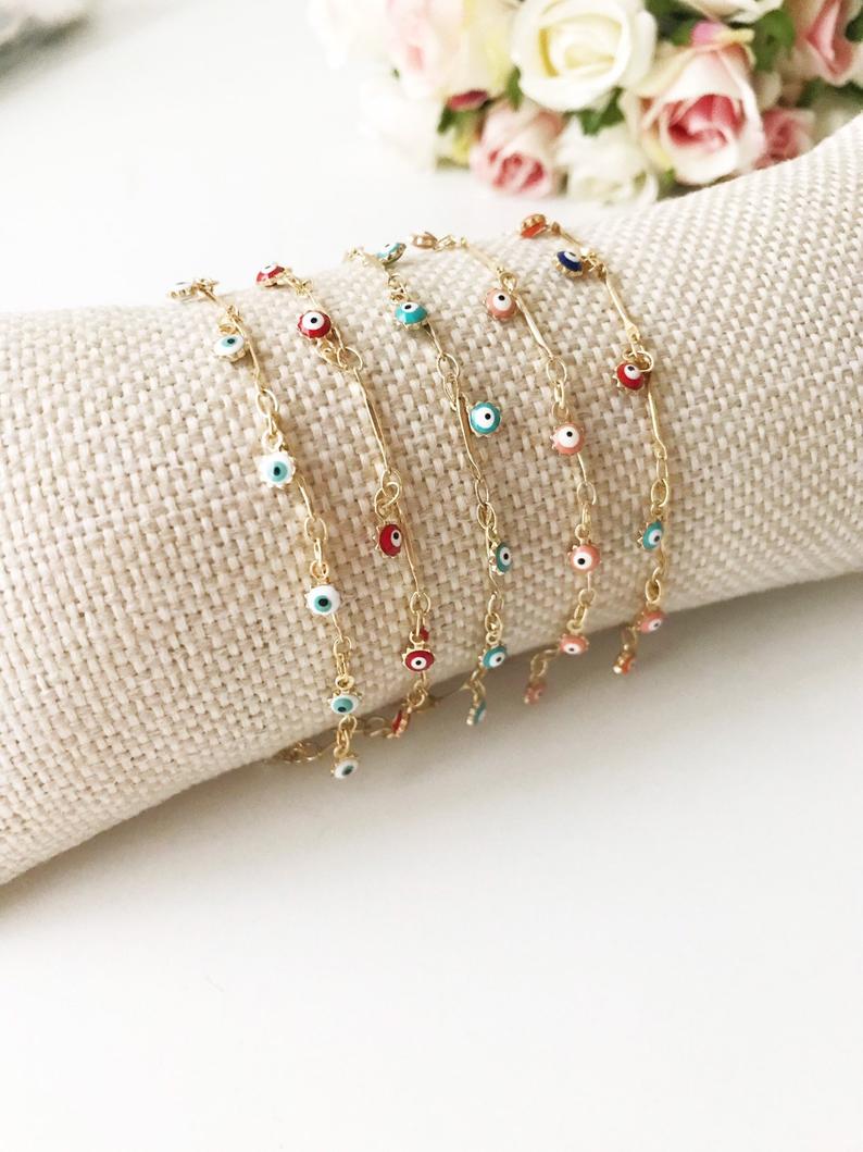 A delicate Evil Eye Bracelet featuring a gold chain and tiny blue evil eye bead, showcasing its minimalistic design.