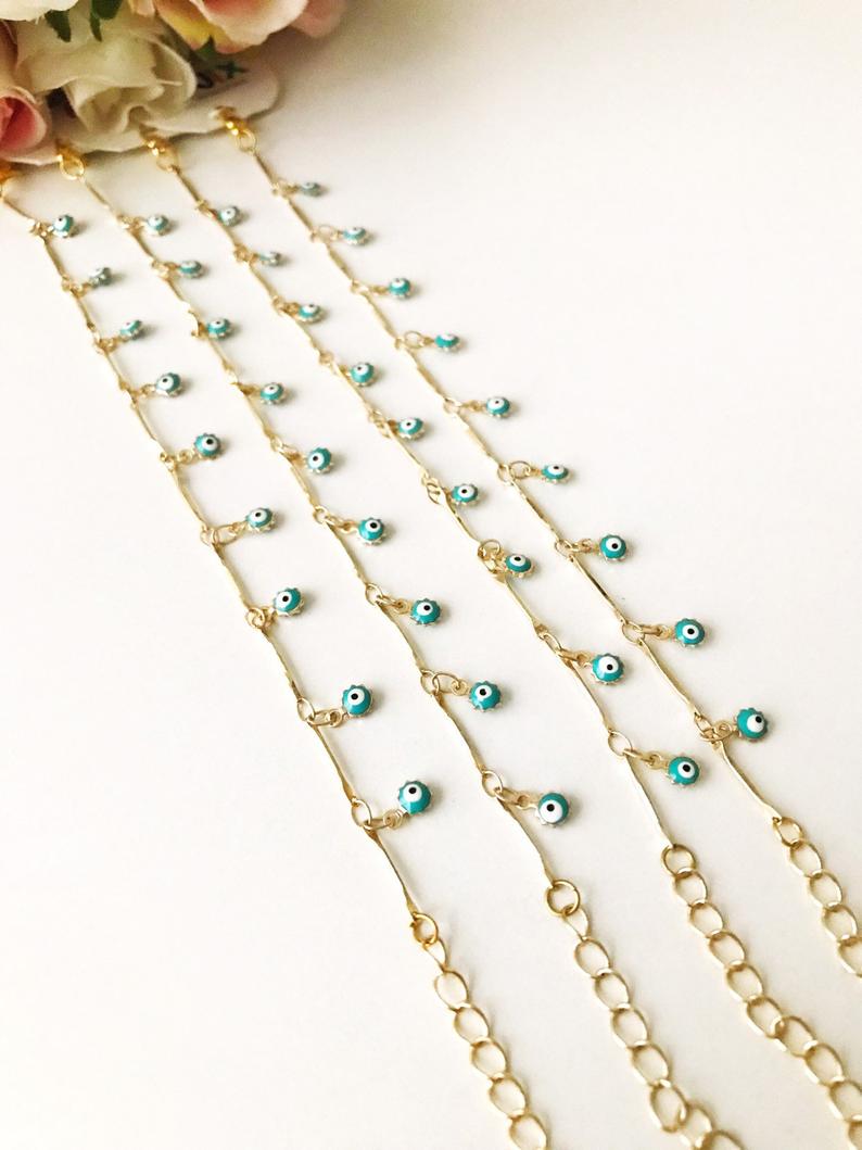A delicate Evil Eye Bracelet featuring a gold chain and tiny blue evil eye bead, showcasing its minimalistic design.