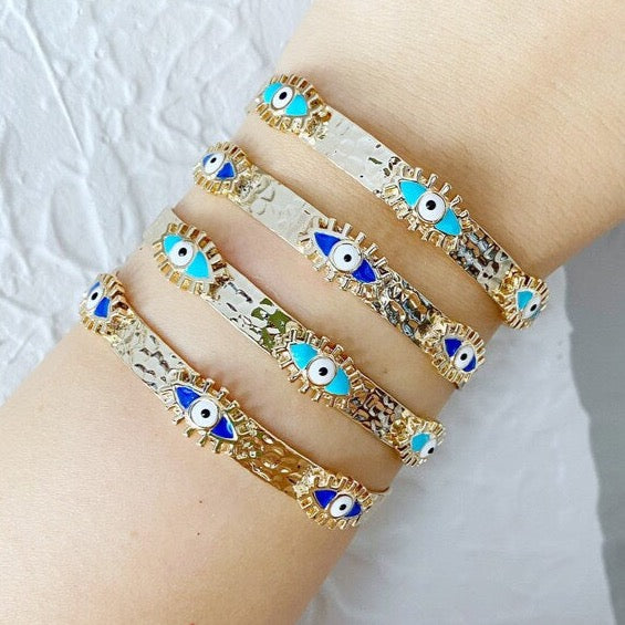 Gold cuff bracelet featuring a movable blue evil eye charm, symbolizing protection and style.