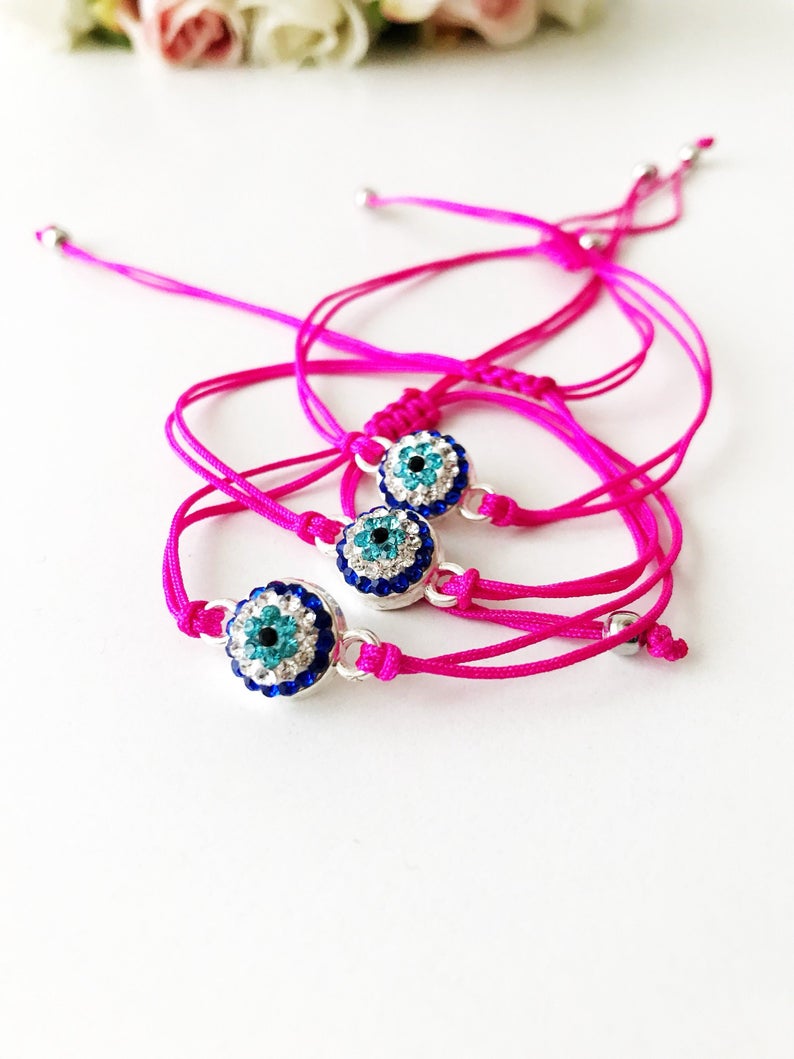 Handmade Evil Eye Bracelet featuring a pink string and a 10mm evil eye charm, adjustable for all wrist sizes.