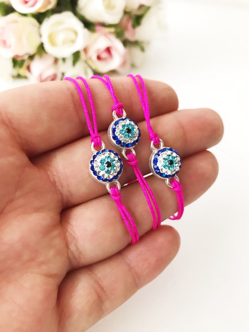 Handmade Evil Eye Bracelet featuring a pink string and a 10mm evil eye charm, adjustable for all wrist sizes.